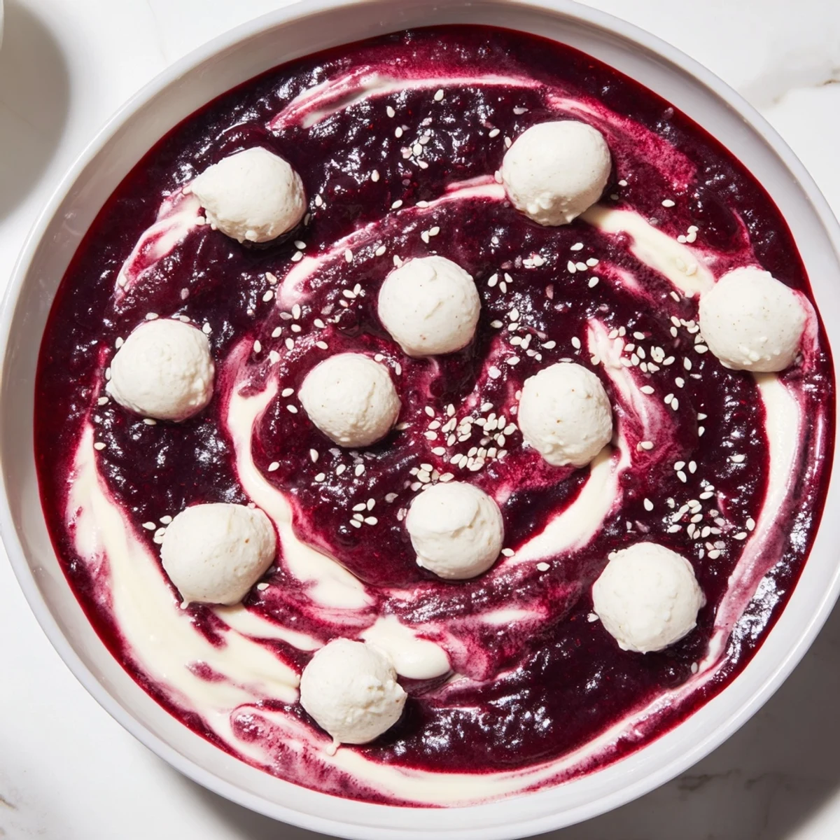 Vibrant The Galaxy Spiral dessert: swirled berry jam with creamy yogurt, sesame seeds, and goat cheese.