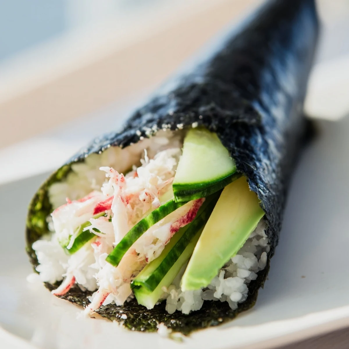 A hand holding a crisp Sushi Rice Hand Roll, highlighting the nori wrapper and the colorful interior of sushi rice and fillings.