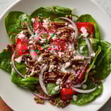 Close-up of a colorful Strawberry Spinach Salad, perfect for summer, drizzled with poppy seed dressing.