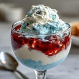 Festive Red, White, and Blue Layered Jello Cups: Clear cups showcase colorful Jello stripes, topped with whipped cream and fresh berries for a showstopping treat.
