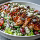 Classic Greek salad with grilled chicken breast, crisp cucumbers, ripe tomatoes, and Kalamata olives, drizzled with zesty dressing.  