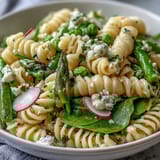 Bright pasta salad with lemon vinaigrette and radishes, tossed with sugar snap peas and baby spinach for a refreshing dish.