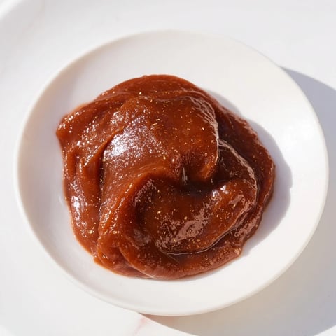 A close-up of Emirati Al Madrooba, a smooth, date-based paste with golden ghee swirls and cardamom.