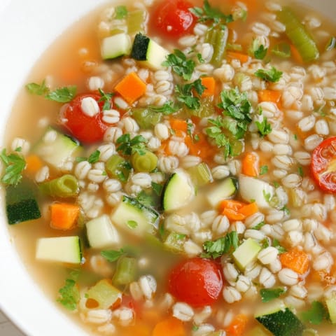 A close-up of a delightful simple homemade grain and vegetable soup, fresh herbs topping the warm broth.