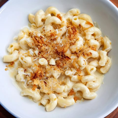 A close-up of a steaming bowl of Tinis Recession Mac, featuring melted cheddar and American cheese.
