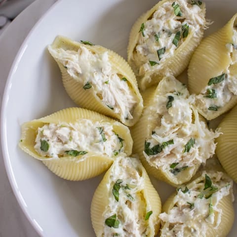 A baking dish filled with golden brown Marry Me Chicken Stuffed Shells, ready for serving with garlic bread.