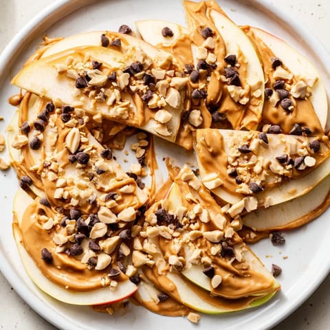 Creamy peanut butter coats apple slices in these delightful Peanut Butter Apple Nachos, topped with chopped nuts.
