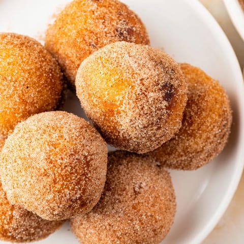 Freshly made air fryer cinnamon donuts, a delicious quick treat, coated in sweet, spiced cinnamon sugar.