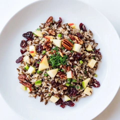 Wild Rice Harvest Salad in a white ceramic bowl, with fresh parsley, chives, and diced apple, perfect for an autumn side dish.