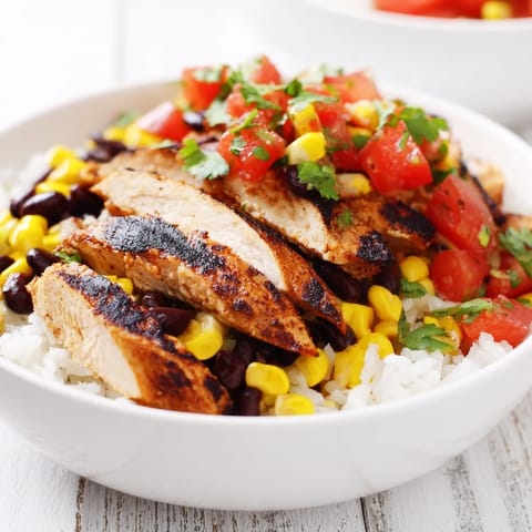 This hearty Spicy Chicken Burrito Bowl features juicy chicken, creamy avocado slices, and a generous spoonful of zesty salsa.