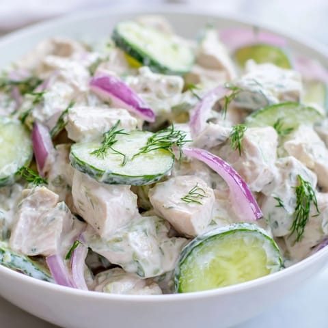 Creamy cucumber chicken salad served in a white bowl, with a side of whole-grain crackers for dipping into the protein-packed yogurt dressing.
