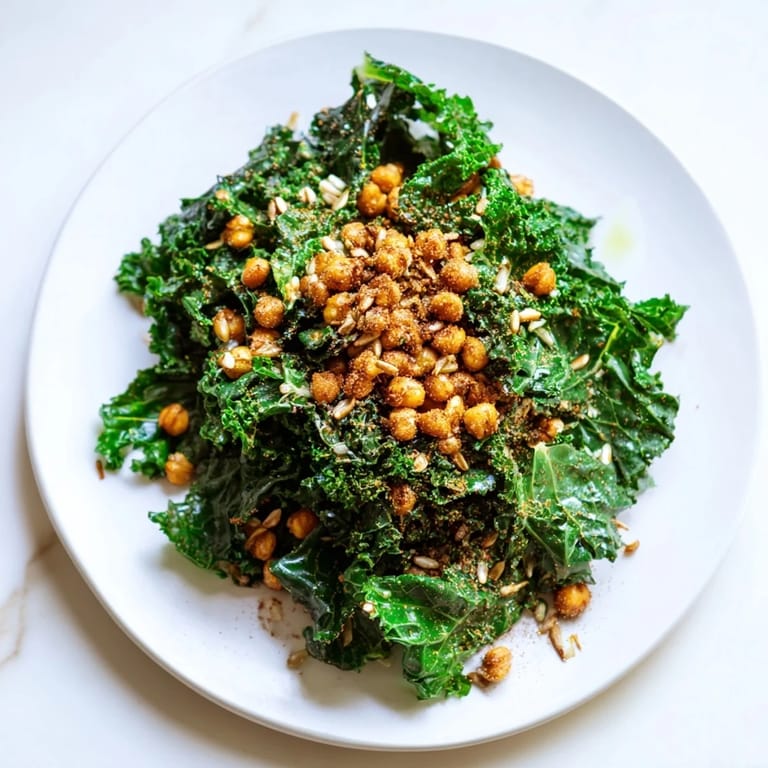 A bowl of warm kale salad with crispy chickpeas, drizzled in lemon dressing, ready to eat!