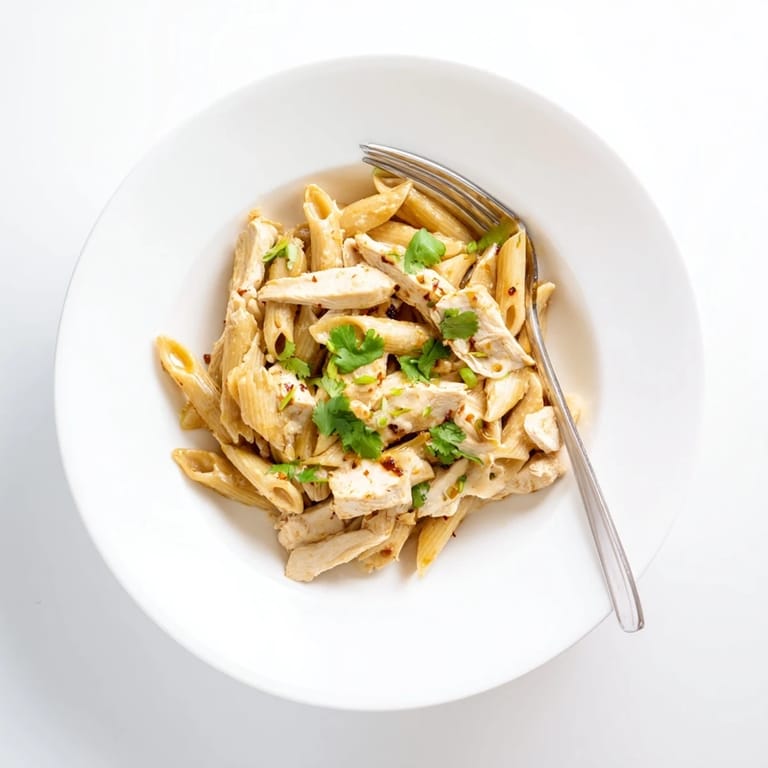 Savory honey chipotle chicken pasta served in a white bowl, steam rising from the creamy sauce and Parmesan garnish.