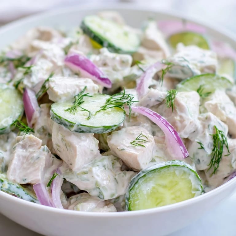 Creamy cucumber chicken salad served in a white bowl, with a side of whole-grain crackers for dipping into the protein-packed yogurt dressing.