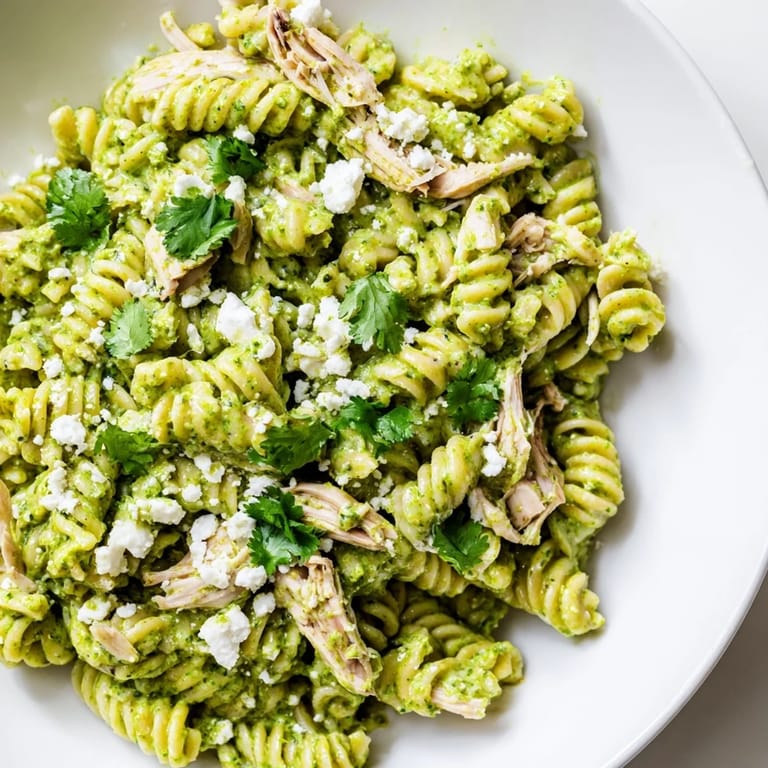 Close-up of creamy Cilantro Lime Chicken Pasta tossed with rotini and shredded chicken, drizzled with bright green cilantro sauce.