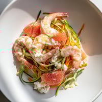 Vibrant "The Coral Reef" dish features pink shrimp, citrus, and bubbling Gruyère, a beautiful, unique main course.